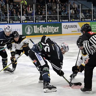 Eishockeyspieler der KSW IceFighters Leipzig während eines Spiels auf dem Eis, umgeben von Schiedsrichtern und Zuschauern.