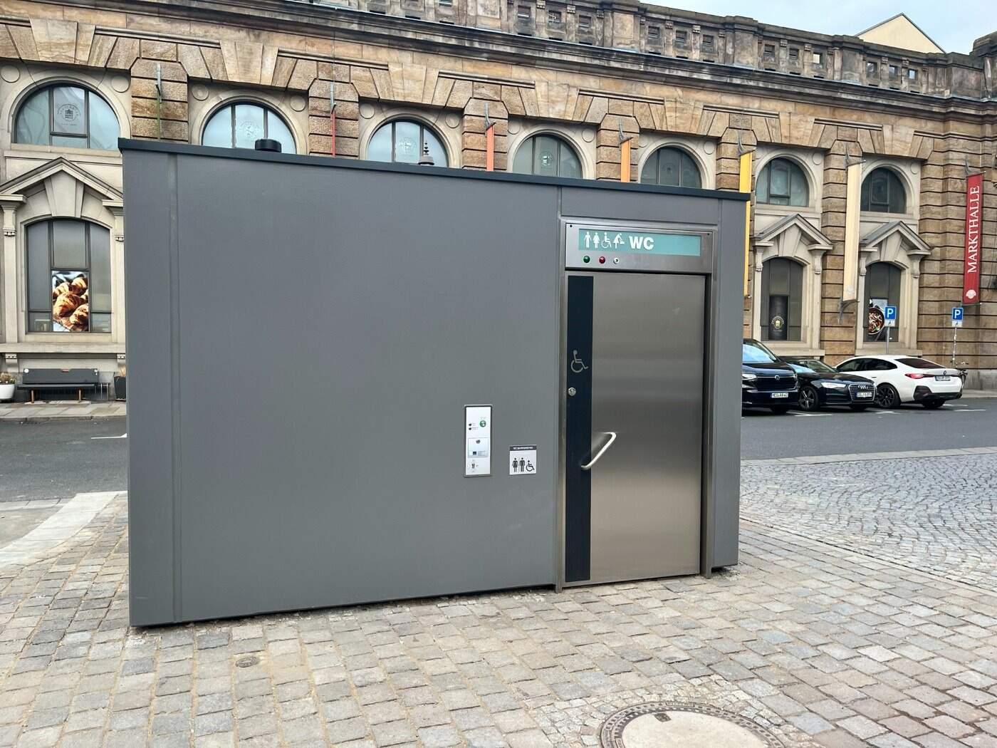 Graue, moderne öffentliche Toilettenanlage in der Ritterstraße Dresden-Neustadt vor der historischen Markthalle; barrierefreies Stadt-WC aus Metall.