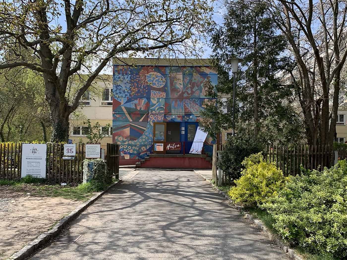 Fassade des Johannstädter Kulturtreffs an der Elisenstraße 35 mit einem großflächigen, bunten Wandbild am Eingangsbereich, umgeben von Bäumen und Hecken.