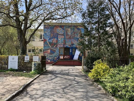 Fassade des Johannstädter Kulturtreffs an der Elisenstraße 35 mit einem großflächigen, bunten Wandbild am Eingangsbereich, umgeben von Bäumen und Hecken.
