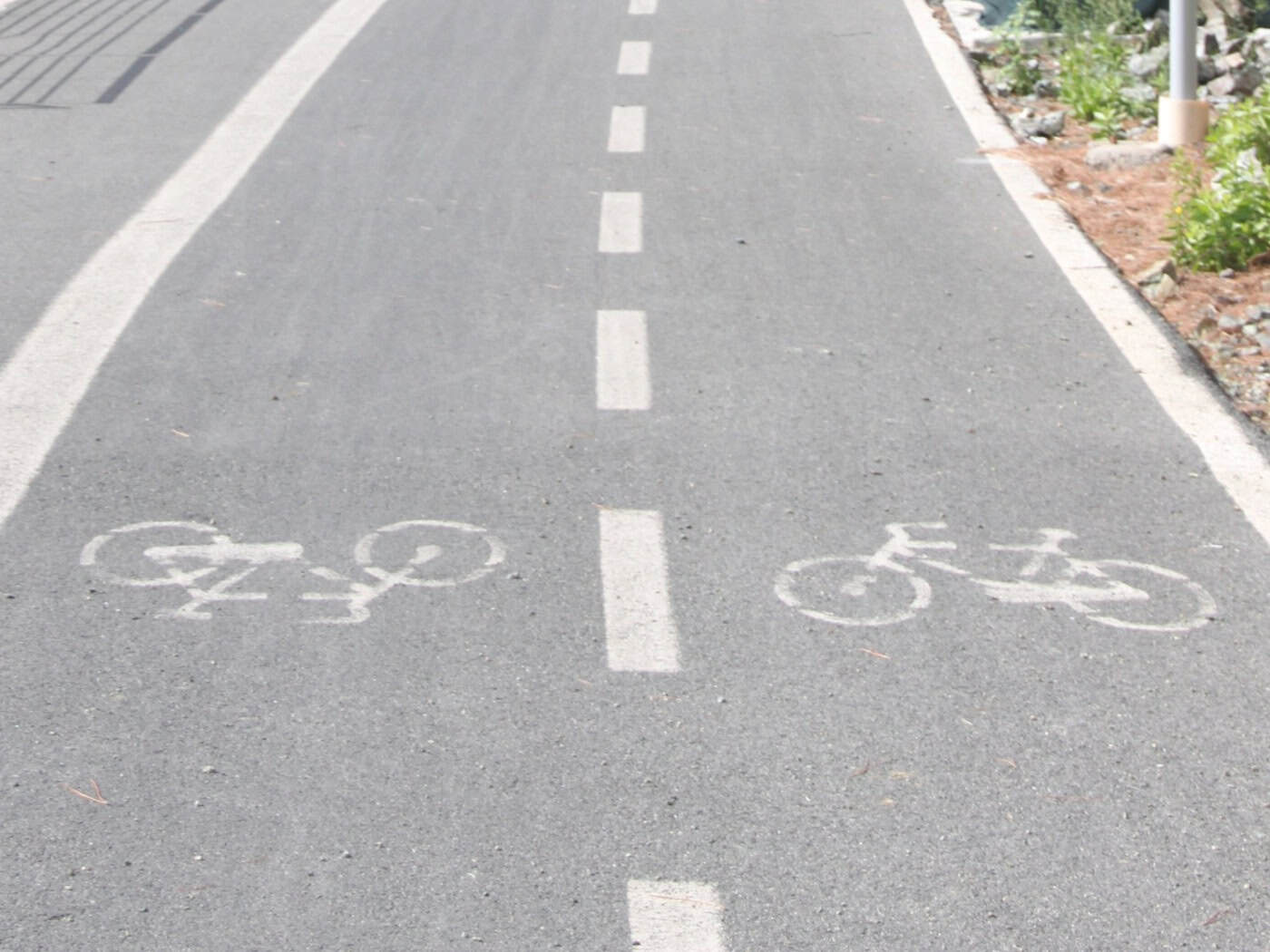 Ein asphaltierter Radweg mit zwei markierten Fahrspuren führt auf einen beleuchteten Tunnel zu – Symbolbild für den Ausbau der Radinfrastruktur.
