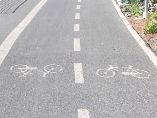Ein asphaltierter Radweg mit zwei markierten Fahrspuren führt auf einen beleuchteten Tunnel zu – Symbolbild für den Ausbau der Radinfrastruktur.