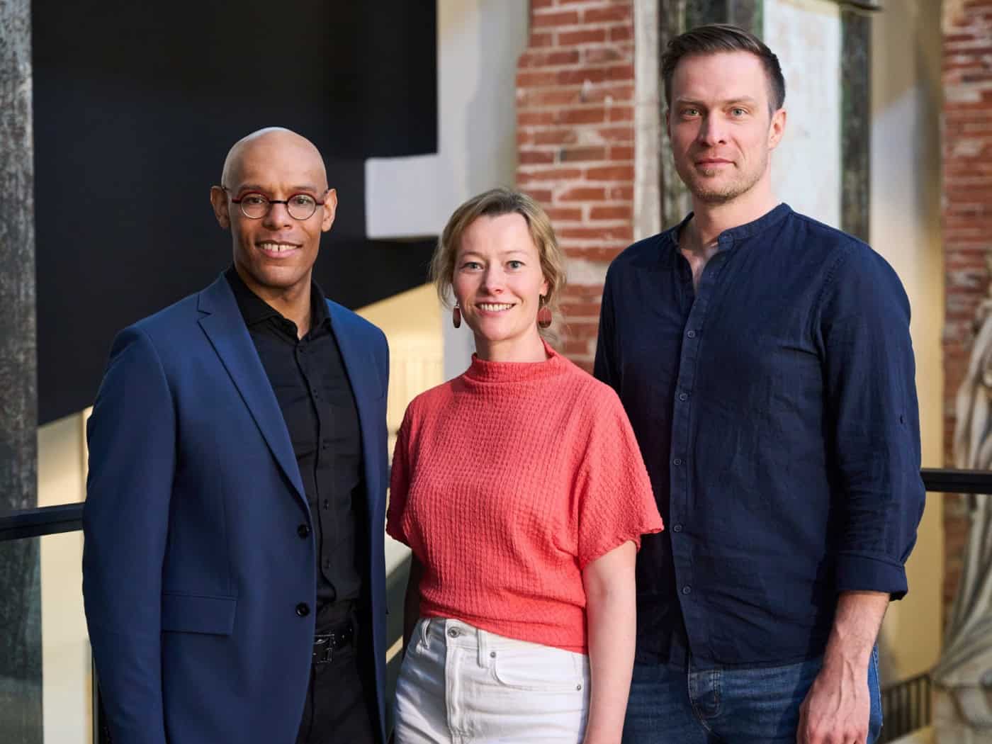 Michael Ellis Ingram (links), Kathrin Kondaurow (Mitte) und Matthias Reichwald (rechts) stehen gemeinsam vor dem Logo der Staatsoperette Dresden bei der Vorstellung des neuen Programms.