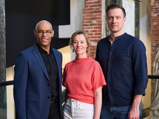 Michael Ellis Ingram (links), Kathrin Kondaurow (Mitte) und Matthias Reichwald (rechts) stehen gemeinsam vor dem Logo der Staatsoperette Dresden bei der Vorstellung des neuen Programms.