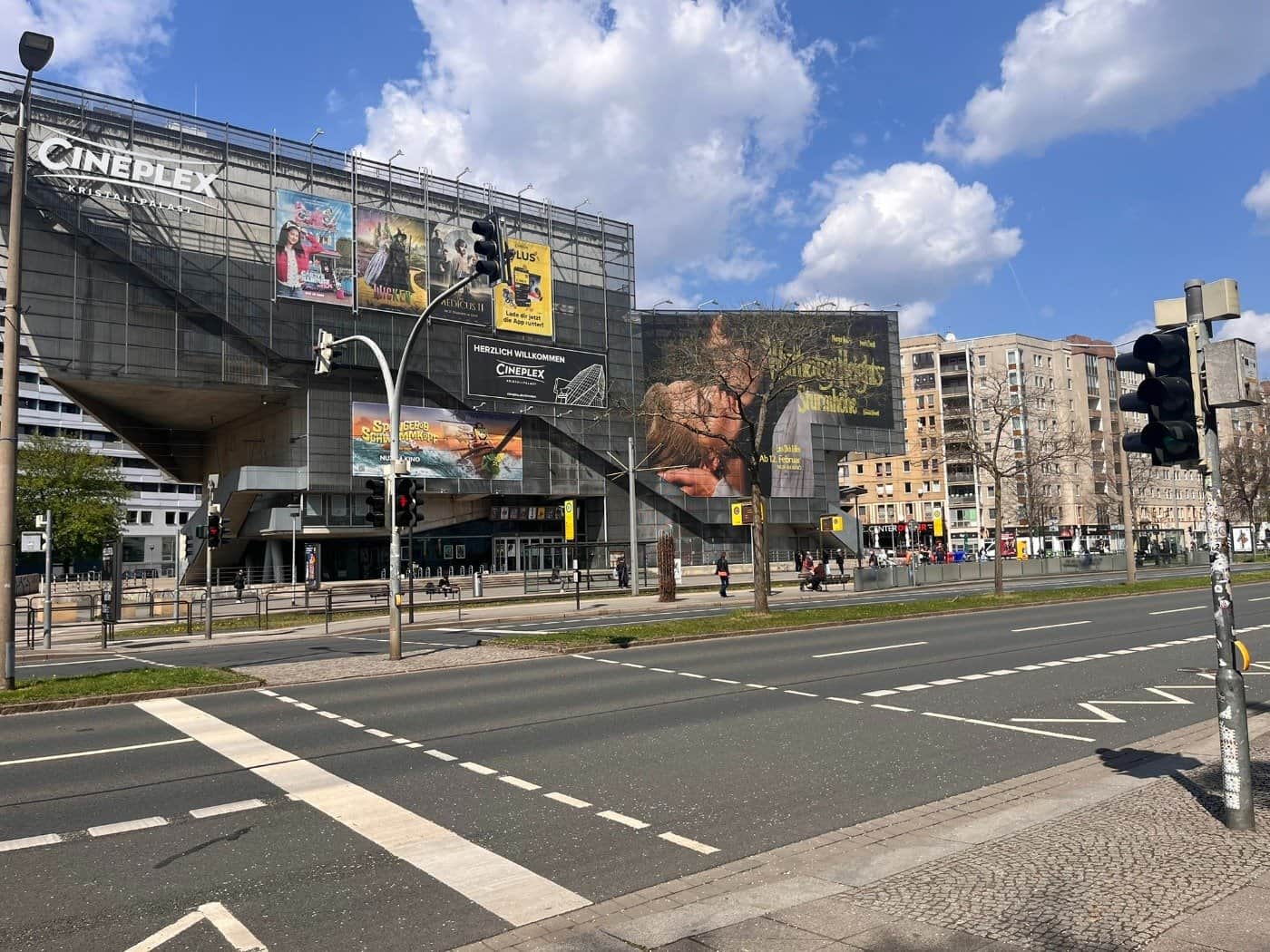 Blick auf die mehrspurige St. Petersburger Straße in Dresden mit dem markanten Gebäude des Cineplex Kristallpalast im Hintergrund.  Im Vordergrund sind Ampelanlagen und der Fußgängerüberweg im Bereich der Haltestelle Walpurgisstraße zu sehen, an dem sich der Unfall ereignete.