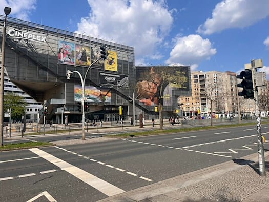 Blick auf die mehrspurige St. Petersburger Straße in Dresden mit dem markanten Gebäude des Cineplex Kristallpalast im Hintergrund.  Im Vordergrund sind Ampelanlagen und der Fußgängerüberweg im Bereich der Haltestelle Walpurgisstraße zu sehen, an dem sich der Unfall ereignete.