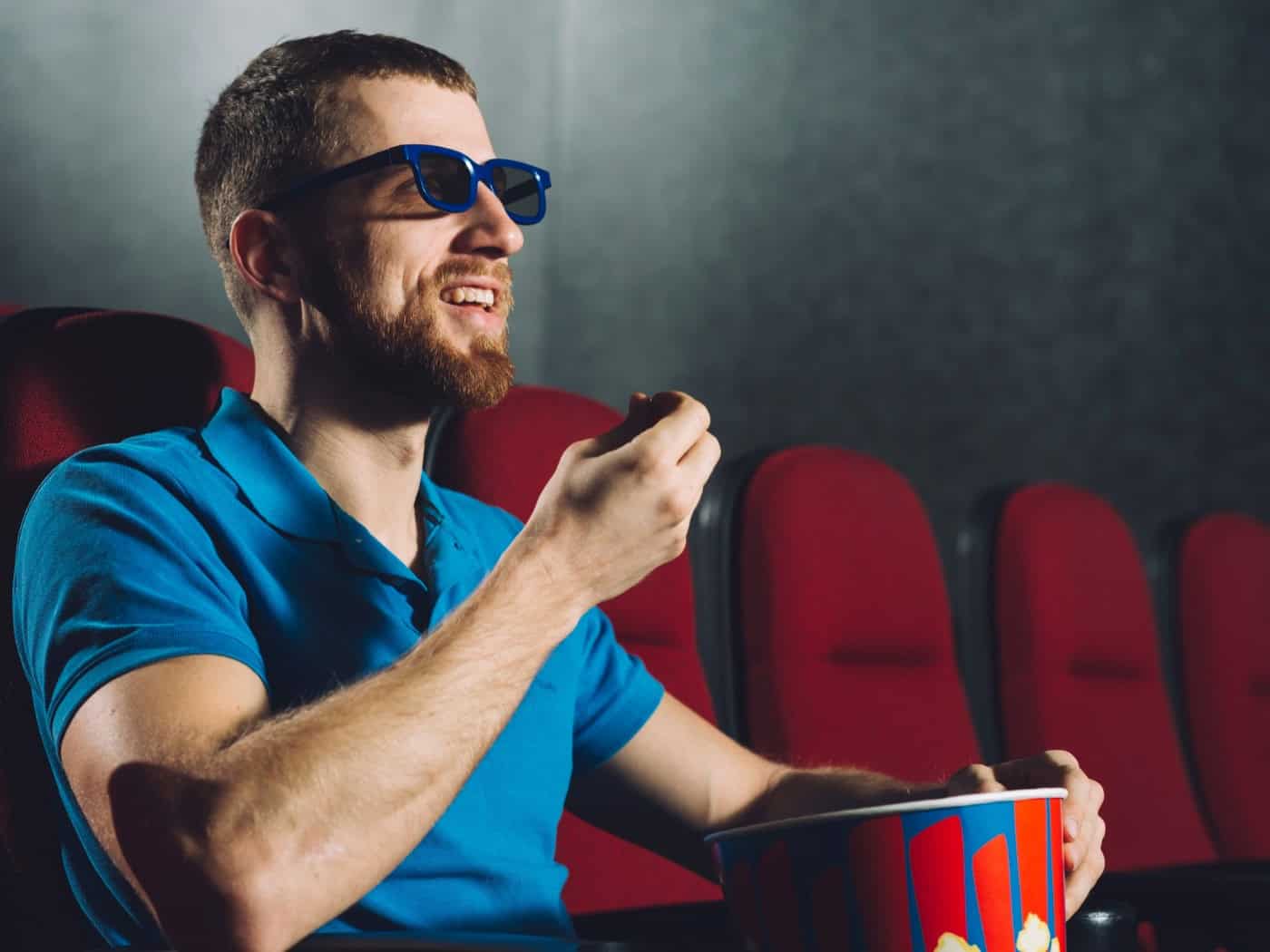 Mann mit 3D-Brille isst Popcorn im Kino – perfekt für Casino-Filme