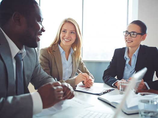 Drei Geschäftsleute diskutieren im Meeting über B2B-Lizenzstrategien und Verträge