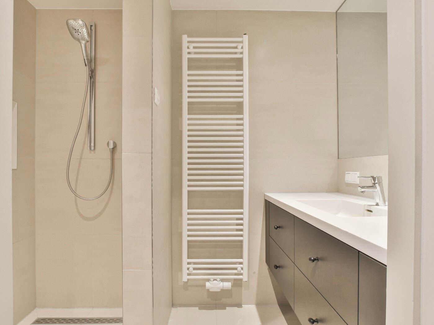 Ein modern gestaltetes, helles und barrierefreies Badezimmer mit ebenerdiger Dusche und Sicherheitsgriffen.