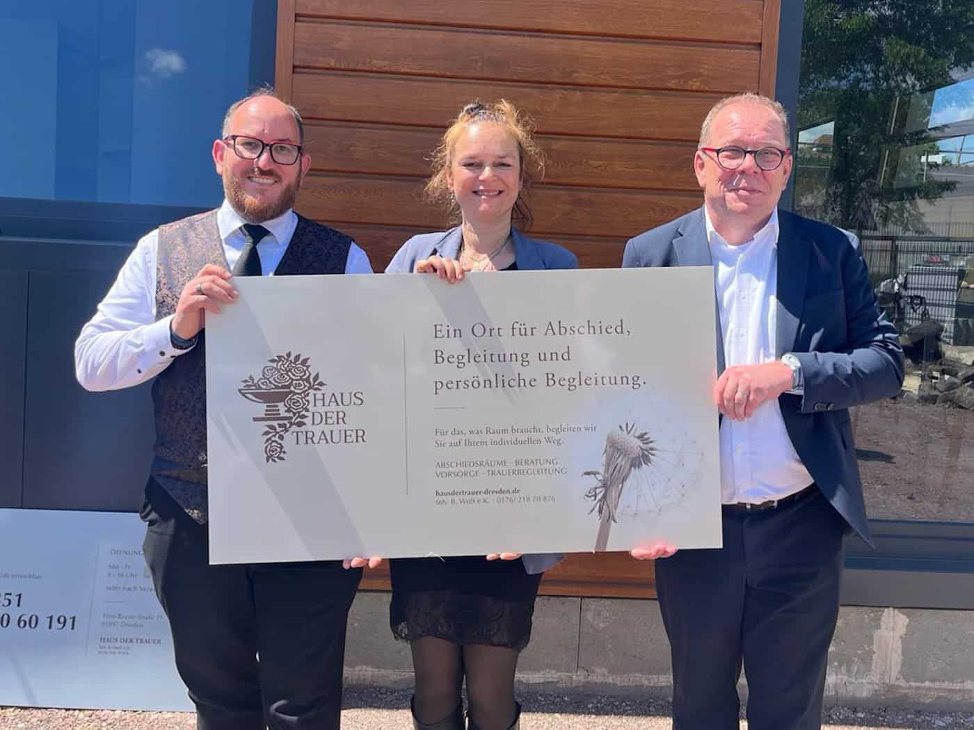 Drei lächelnde Personen stehen nebeneinander in den sanierten, lichtdurchfluteten Räumen des neuen Instituts: Links das Inhaber-Ehepaar Adriana und Benjamin Wolf, rechts im Bild der Beteiligungsmanager der SIB Innovations- und Beteiligungsgesellschaft.