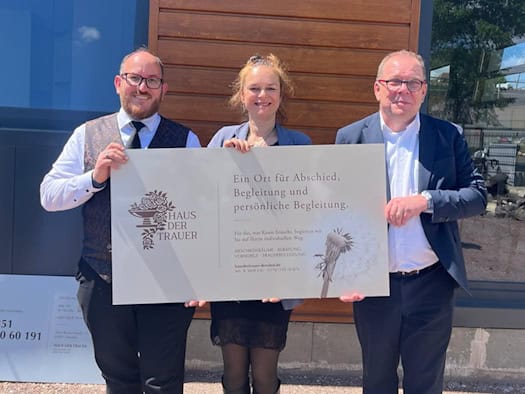 Drei lächelnde Personen stehen nebeneinander in den sanierten, lichtdurchfluteten Räumen des neuen Instituts: Links das Inhaber-Ehepaar Adriana und Benjamin Wolf, rechts im Bild der Beteiligungsmanager der SIB Innovations- und Beteiligungsgesellschaft.