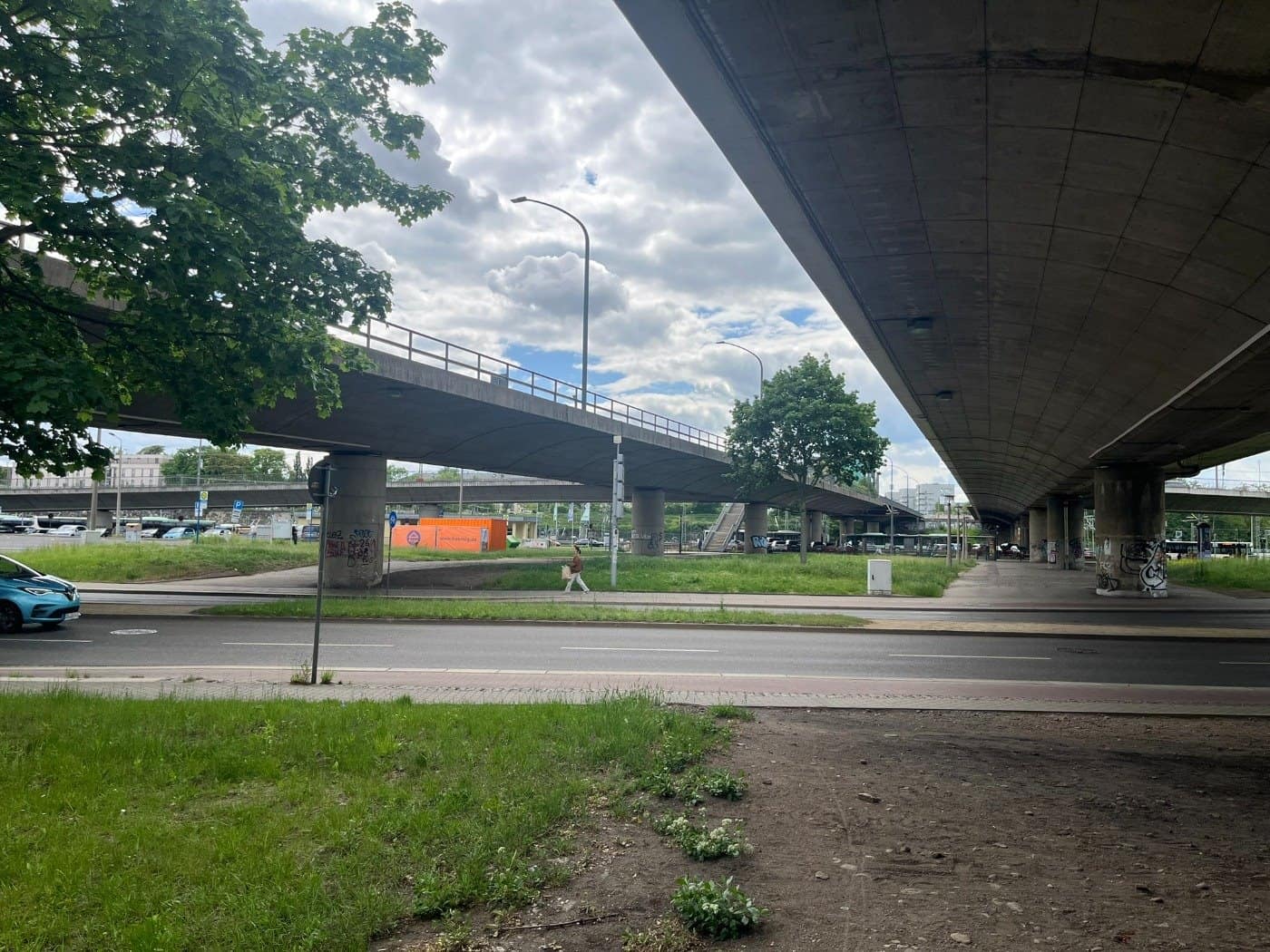 Unteransicht der weitläufigen Betonkonstruktion und massiven Pfeiler der Brücke Budapester Straße in Dresden, umgeben von Grünflächen.