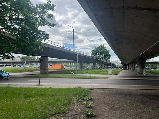 Unteransicht der weitläufigen Betonkonstruktion und massiven Pfeiler der Brücke Budapester Straße in Dresden, umgeben von Grünflächen.
