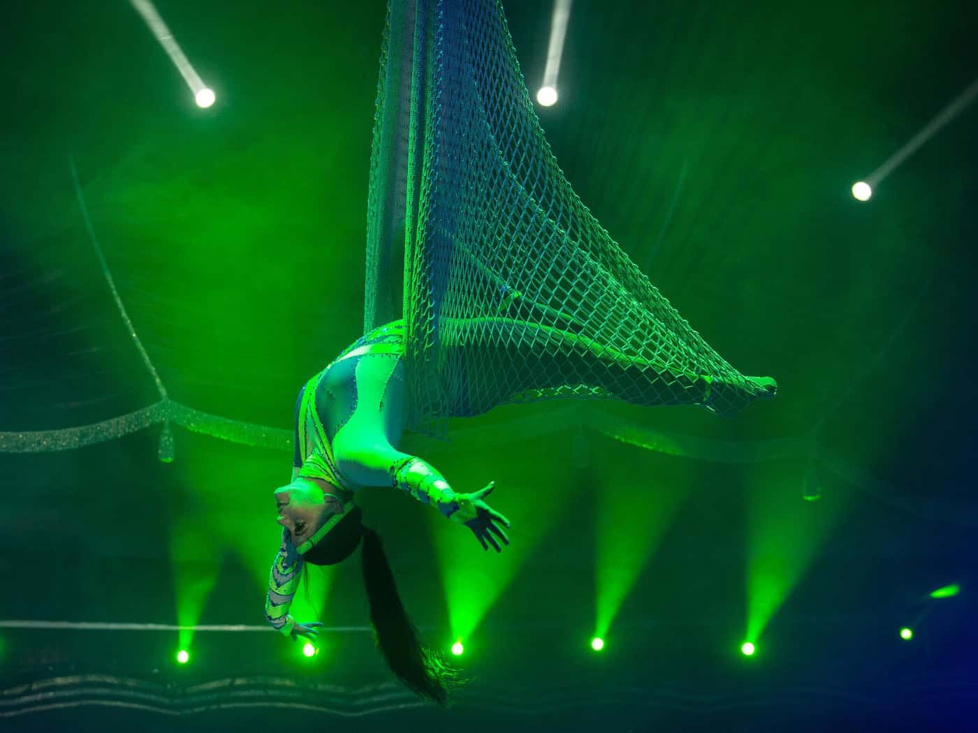 Artistin bei einer waghalsigen Vorführung am Schwungtrapez unter der Zirkuskuppel des Circus ARENA.