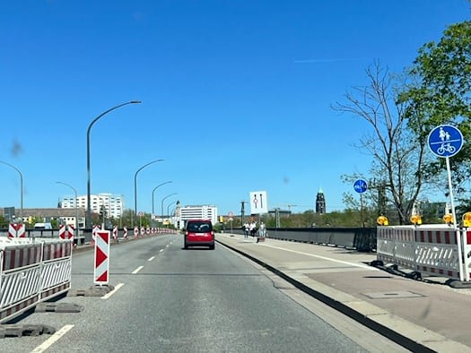 Blick aus der Windschutzscheibe eines Fahrzeugs auf eine Dresdner Straße mit Fahrbahnmarkierungen und Hinweisschildern im Bereich der Brückensperrung an der Ammonstraße.