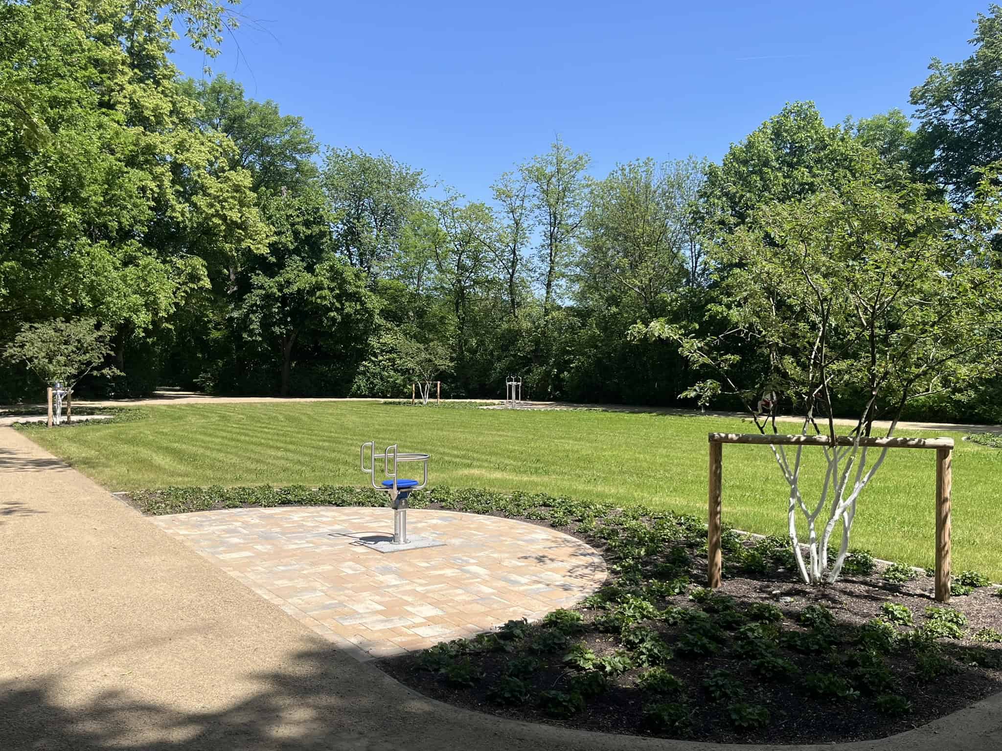 Outdoor-Fitness im Toeplerpark Dresden Ein modernes Fitnessgerät auf einer gepflasterten Fläche am Rande einer großen, gepflegten Rasenfläche im Toeplerpark Tolkewitz.