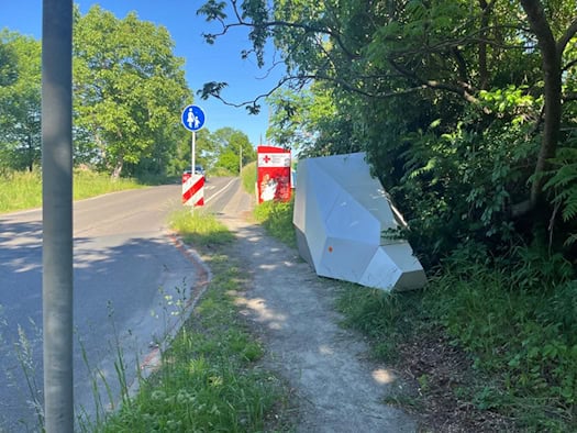 Der Enforcement-Trailer „HWI-VE 159“ steht versteckt hinter einem Altkleidercontainer am Straßenrand der Boderitzer Straße in Dresden.