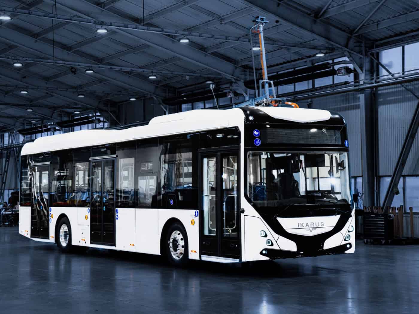 Ein neuer Omnibus mit weißer Lakierung und schwarzen Türrahmen der Firma Ikarus steht in einer Halle