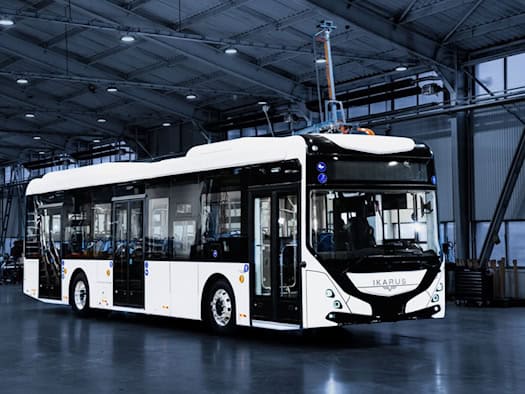 Ein neuer Omnibus mit weißer Lakierung und schwarzen Türrahmen der Firma Ikarus steht in einer Halle