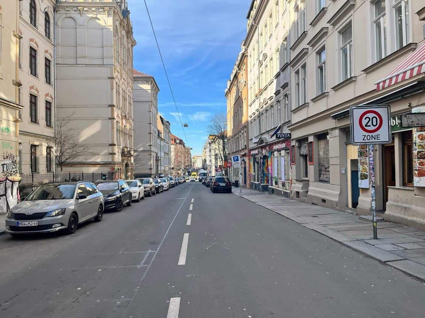 Blick in die Louisenstraße in der Dresdner Neustadt mit geparkten Autos auf beiden Seiten und einem Tempo-20-Zonenschild im Vordergrund; im Hintergrund sind die Fassaden historischer Wohnhäuser unter blauem Himmel zu sehen.