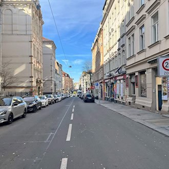 Blick in die Louisenstraße in der Dresdner Neustadt mit geparkten Autos auf beiden Seiten und einem Tempo-20-Zonenschild im Vordergrund; im Hintergrund sind die Fassaden historischer Wohnhäuser unter blauem Himmel zu sehen.
