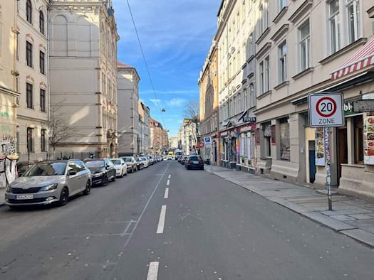 Blick in die Louisenstraße in der Dresdner Neustadt mit geparkten Autos auf beiden Seiten und einem Tempo-20-Zonenschild im Vordergrund; im Hintergrund sind die Fassaden historischer Wohnhäuser unter blauem Himmel zu sehen.