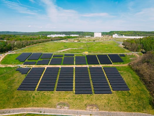 Drohnenaufnahme des weitläufigen Solarparks an der Radeburger Straße in Dresden, der auf dem grünen Gelände einer ehemaligen Deponie errichtet wurde.
