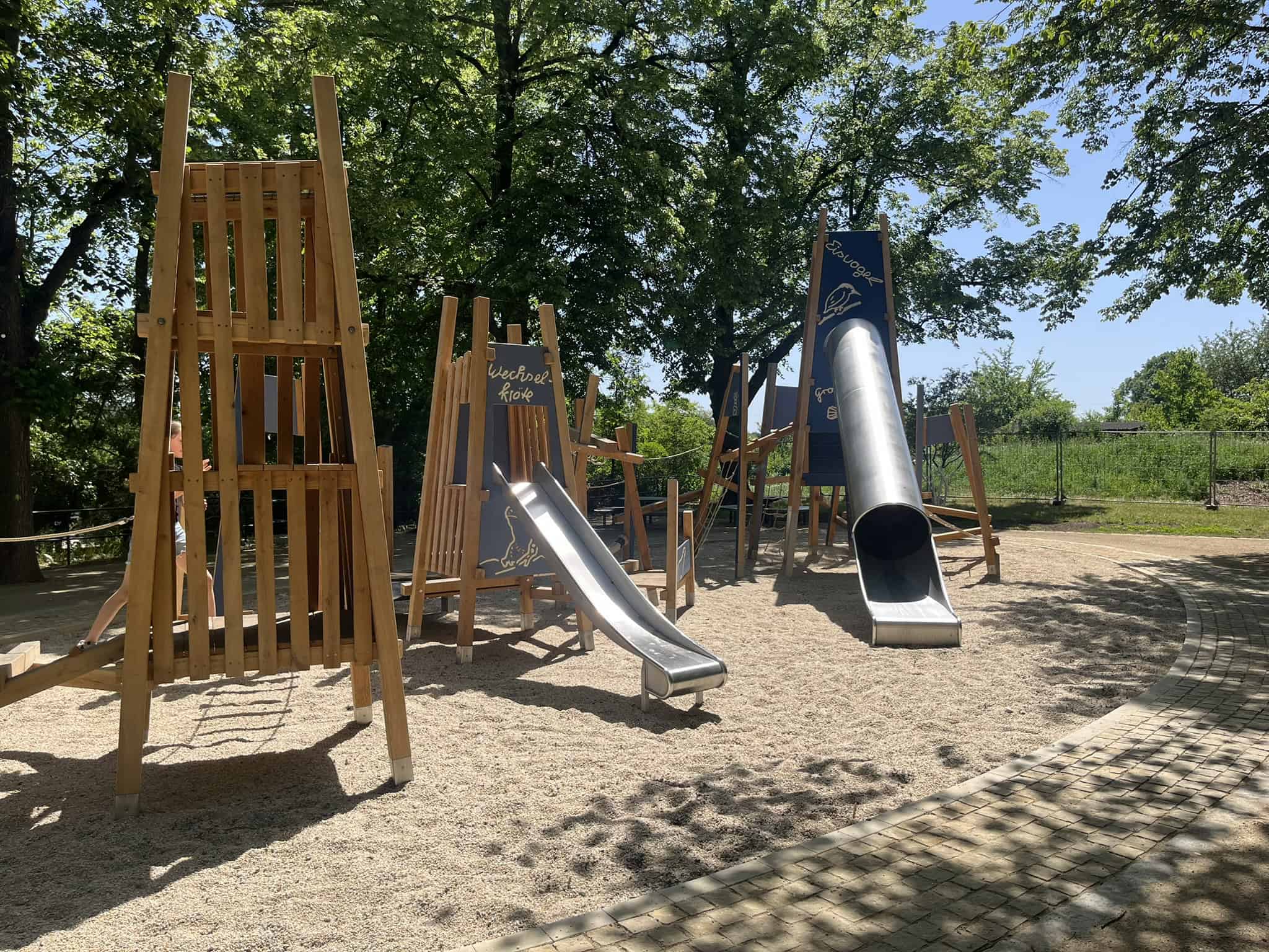 Themenspielplatz „Tiere im Blauen Band“ im Toeplerpark Der neue Themenspielplatz im Dresdner Toeplerpark mit dem großen Kletterturm, der Röhrenrutsche und Balancierstrecken auf hellem Kiesboden.