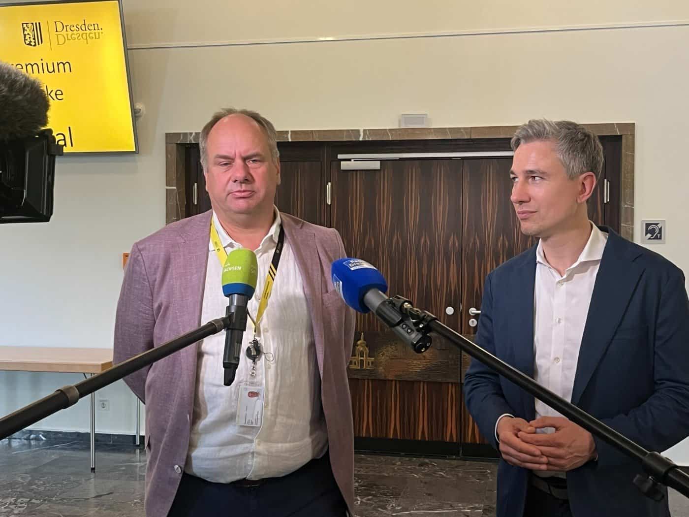Dresdens Oberbürgermeister Dirk Hilbert und Baubürgermeister Stephan Kühn während eines Pressegesprächs vor Mikrofonen zum Neubau der Carolabrücke.
