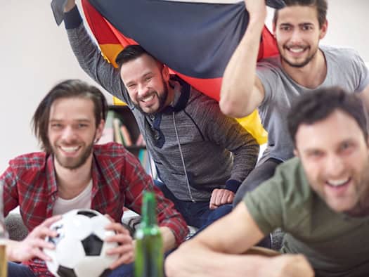 Begeisterte Fans bei einem Public Viewing, die gemeinsam ein Fußballspiel verfolgen und jubeln.