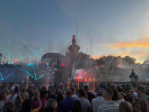 Große Menschenmenge bei einem Open-Air-Konzert von Purple Disco Machine im beleuchteten Innenhof des Dresdner Zwingers mit Lasershow und Wasserfontänen bei Sonnenuntergang.