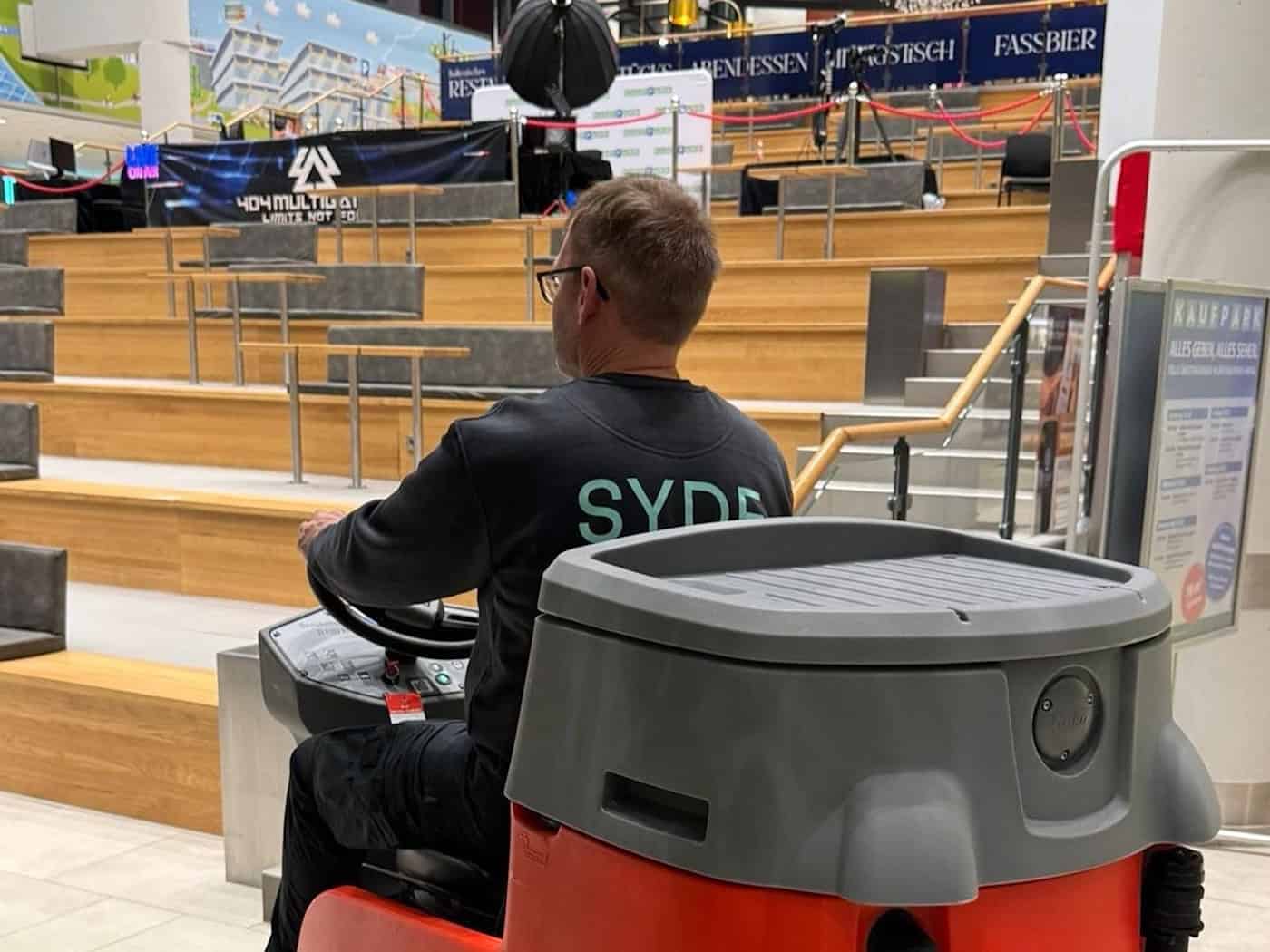 Ein Mitarbeiter der SYDE Cleaning GmbH auf einer Hako-Reinigungsmaschine bei der Bodenpflege in der Kaufpark Arena Dresden.