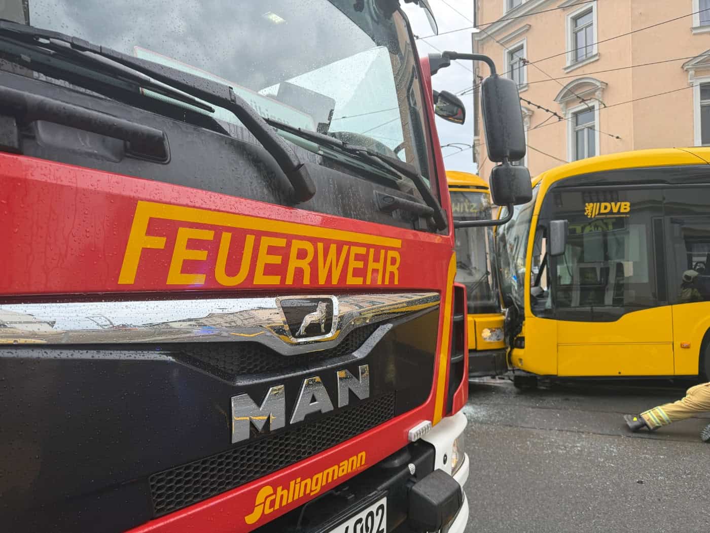 Feuerwehrfahrzeug an der Unfallstelle in Dresden-Briesnitz vor einer entgleisten Straßenbahn und einem beschädigten DVB-Bus.