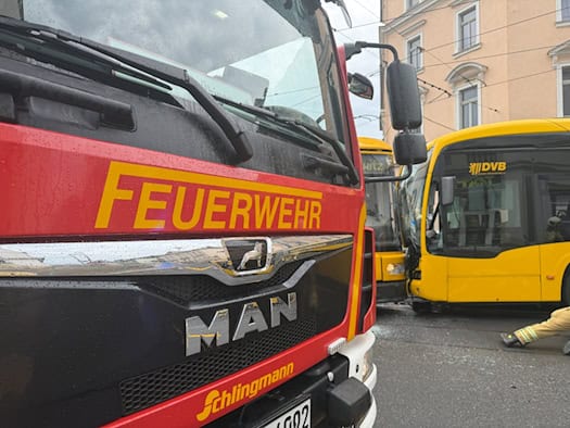 Feuerwehrfahrzeug an der Unfallstelle in Dresden-Briesnitz vor einer entgleisten Straßenbahn und einem beschädigten DVB-Bus.