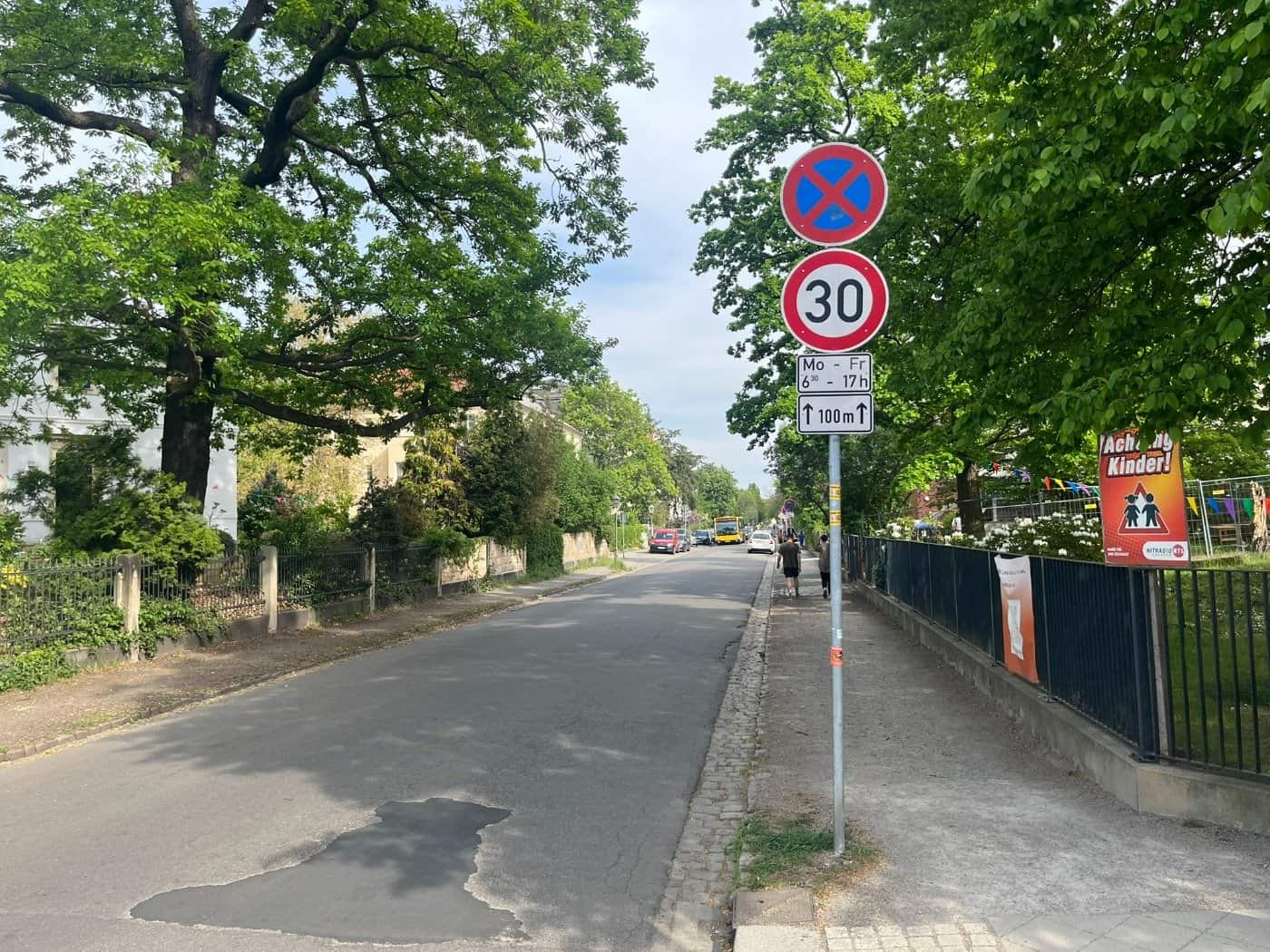 Blick von der Hüblerstraße in die Niederwaldstraße in Dresden-Blasewitz, aufgenommen in Richtung Kretschmerstraße. Ein Verkehrsschild zeigt Tempo 30 (werktags 6:30–17:00 Uhr) für die nächsten 100 Meter. Am rechten Bildrand warnt ein auffälliges orangefarbenes Plakat mit der Aufschrift „Achtung Kinde