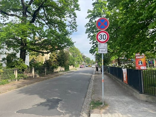 Blick von der Hüblerstraße in die Niederwaldstraße in Dresden-Blasewitz, aufgenommen in Richtung Kretschmerstraße. Ein Verkehrsschild zeigt Tempo 30 (werktags 6:30–17:00 Uhr) für die nächsten 100 Meter. Am rechten Bildrand warnt ein auffälliges orangefarbenes Plakat mit der Aufschrift „Achtung Kinde