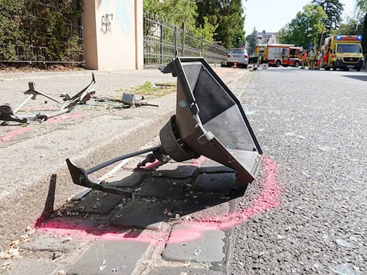 Eine Nahaufnahme der zerstörten historischen Gaslaterne, die nach dem schweren Verkehrsunfall in der Hüblerstraße in Blasewitz auf dem Gehweg liegt. Im Hintergrund sind Feuerwehr und Rettungsdienst im Einsatz.