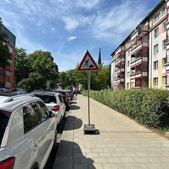 Ein am Straßenrand der Löwenstraße aufgestelltes Baustellenschild, das auf die bevorstehenden Gehwegarbeiten und die damit verbundene Vollsperrung des Fußgängersbereichs hinweist.