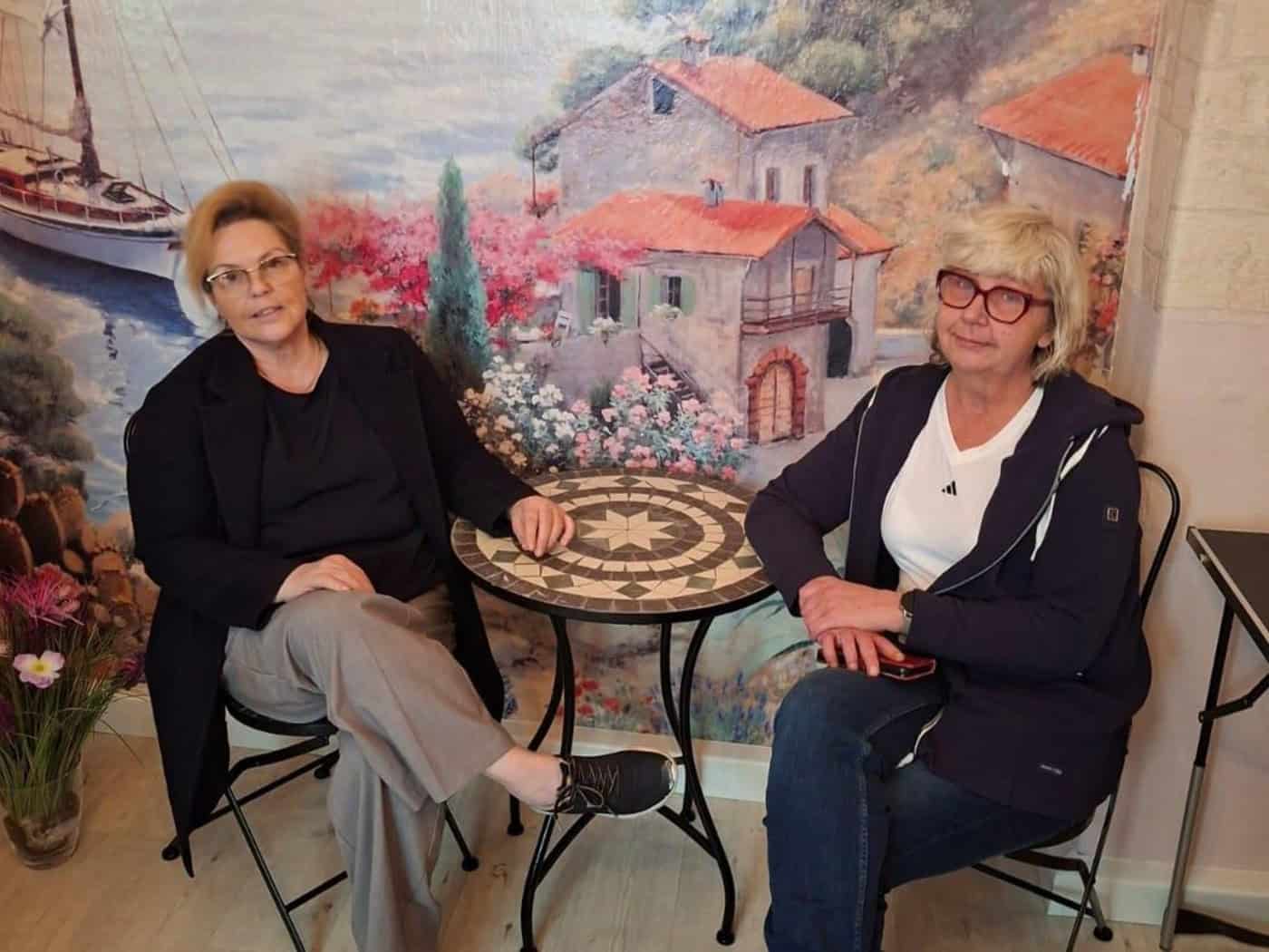 Zwei Frauen mittleren Alters sitzen an einem kleinen Kaffeetisch