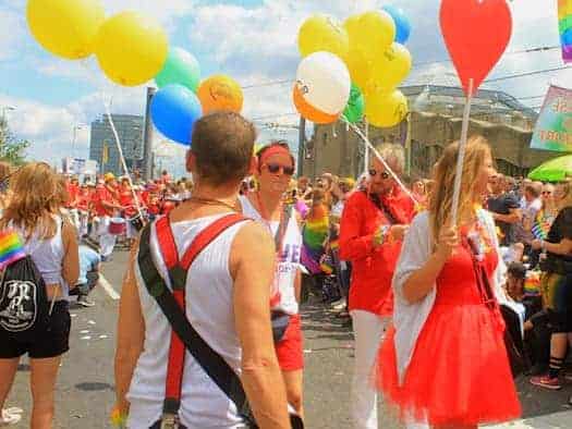 Fröhliche Menschen mit bunten Luftballons und einem großen roten Herz-Luftballon feiern auf einer Christopher-Street-Day-Demonstration (Symbolbild).