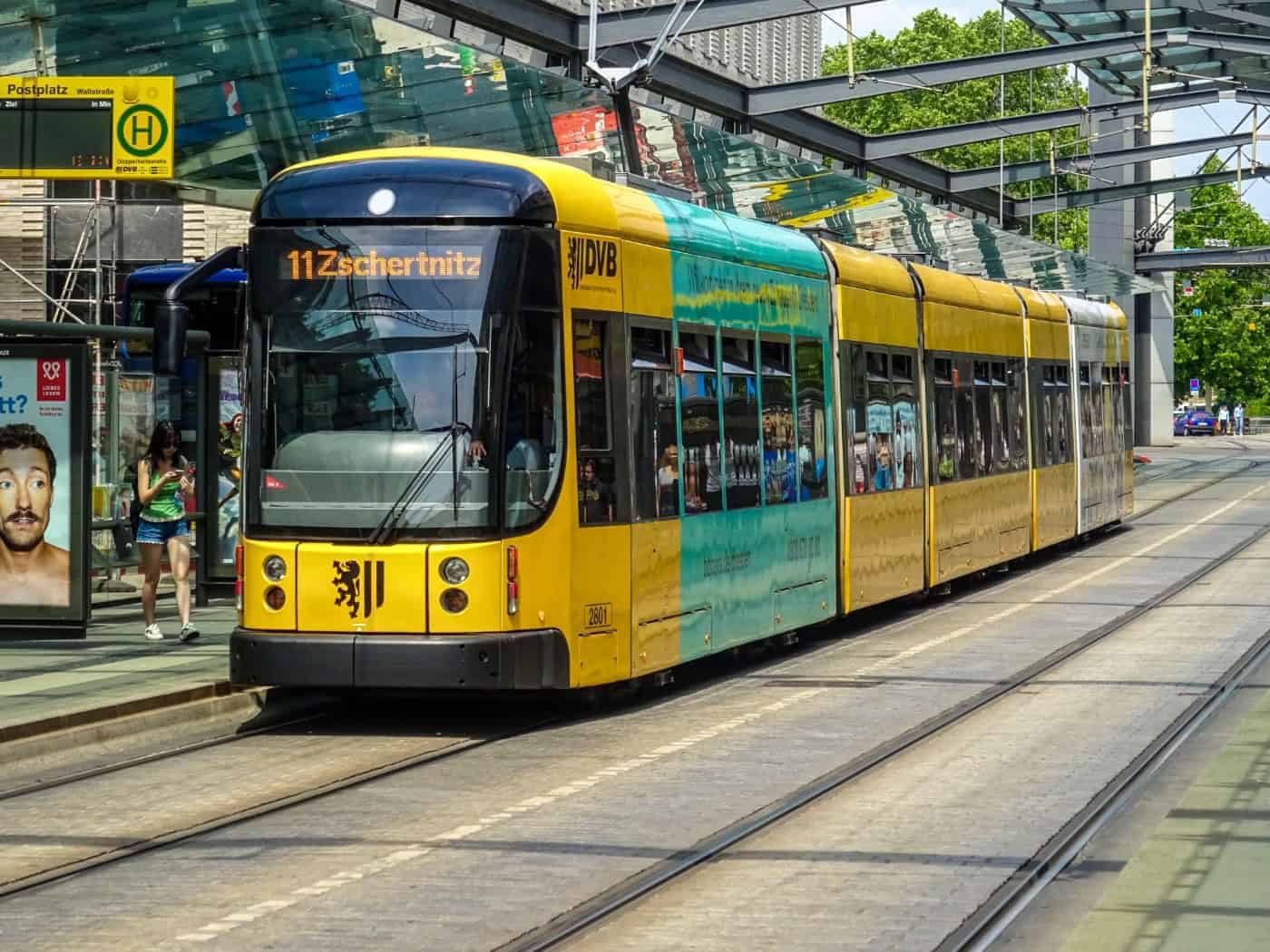 Eine gelb-schwarz-grüne Straßenbahn der Dresdner Verkehrsbetriebe (DVB) der Linie 11 mit dem Ziel Zschertnitz steht an der zentralen Haltestelle Postplatz in Dresden.