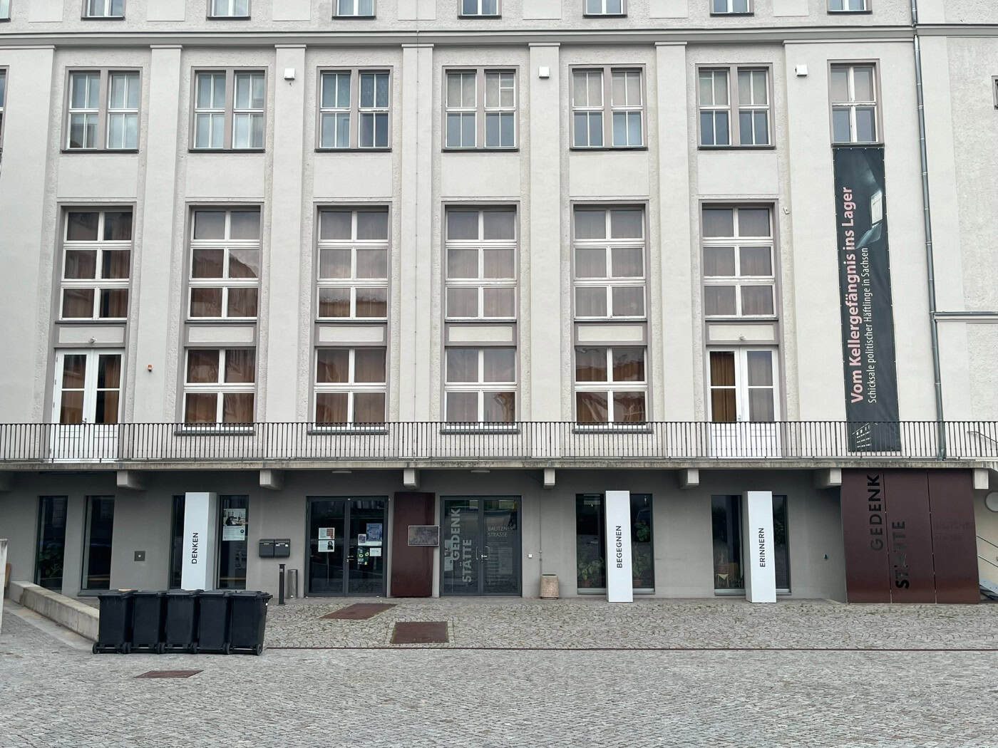 Außenansicht des mehrstöckigen, hell verputzten Gebäudes der Gedenkstätte Bautzner Straße in Dresden bei Tageslicht. Die Fassade ist durch regelmäßige Fensterreihen gegliedert.