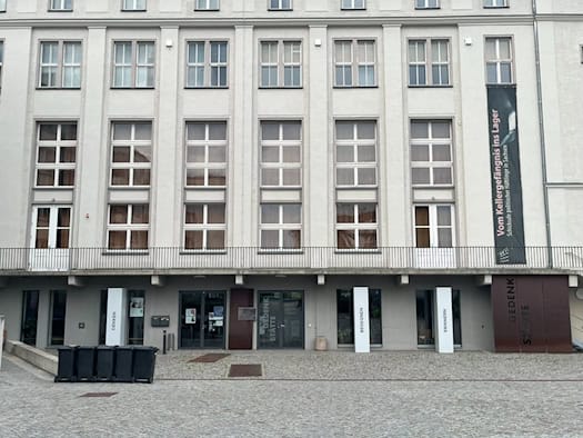 Außenansicht des mehrstöckigen, hell verputzten Gebäudes der Gedenkstätte Bautzner Straße in Dresden bei Tageslicht. Die Fassade ist durch regelmäßige Fensterreihen gegliedert.