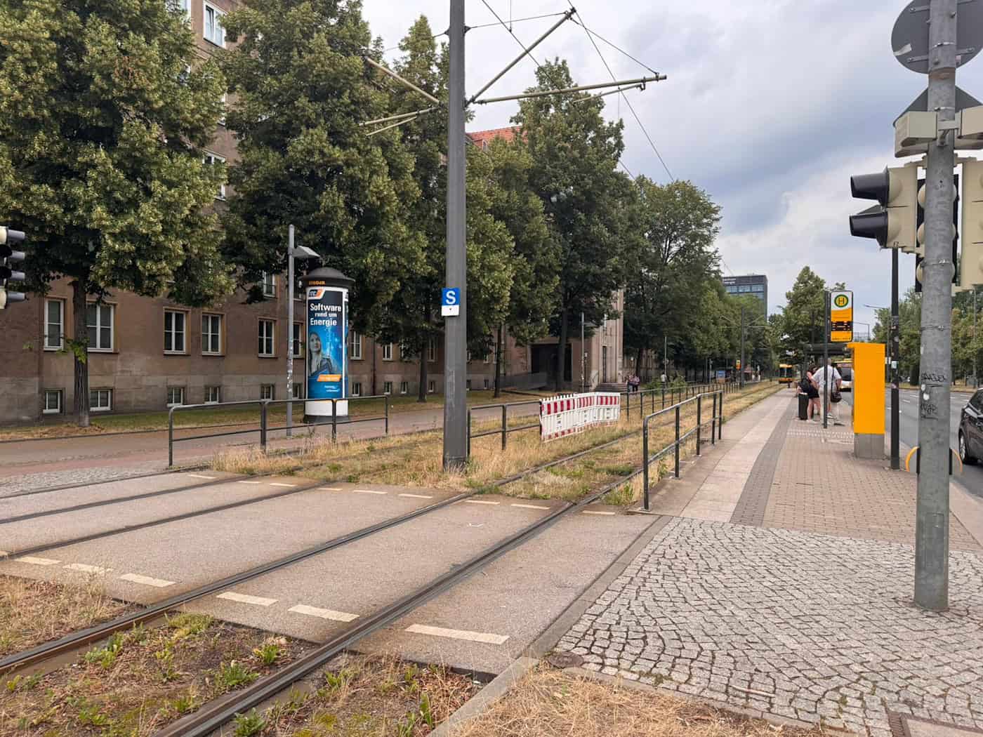 Gleisüberweg an der Straßenbahnhaltestelle Reichenbachstraße Dresden Blick auf den gepflasterten Gleisüberweg für Fußgänger an der Haltestelle Reichenbachstraße. Im Hintergrund sind Absperrgitter am Bahnsteig, eine Litfaßsäule sowie eine Ampel am Straßenrand erkennbar.
