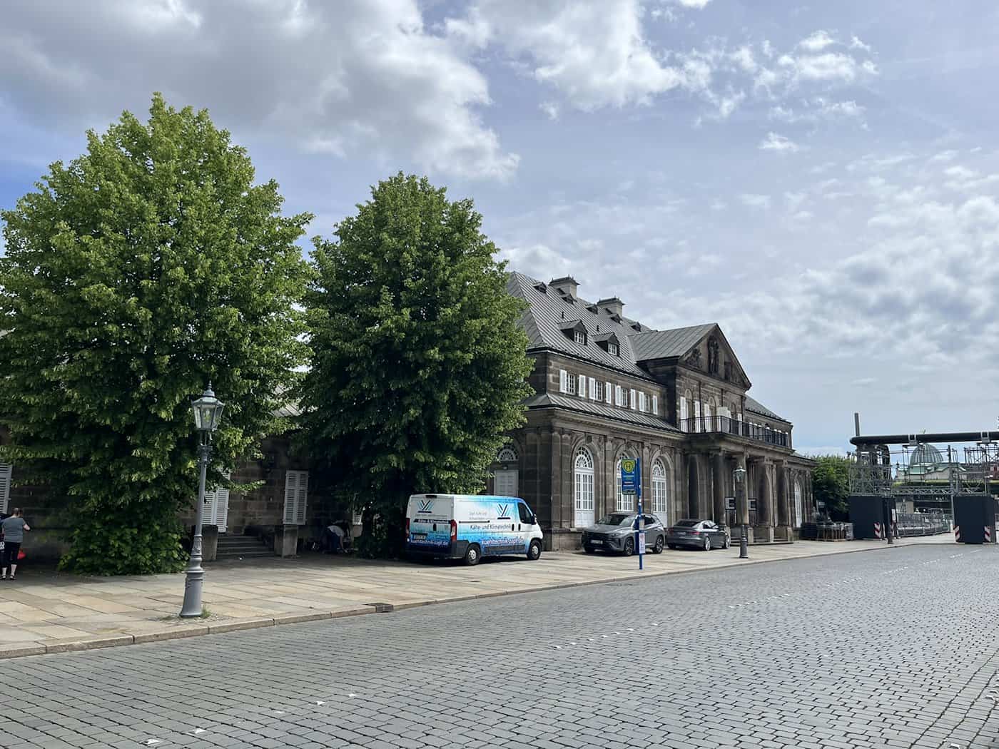 Die neobarocke Sandsteinfassade des Italienischen Dörfchens in Dresden mit einer vorbeifahrenden Pferdekutsche auf dem Theaterplatz.