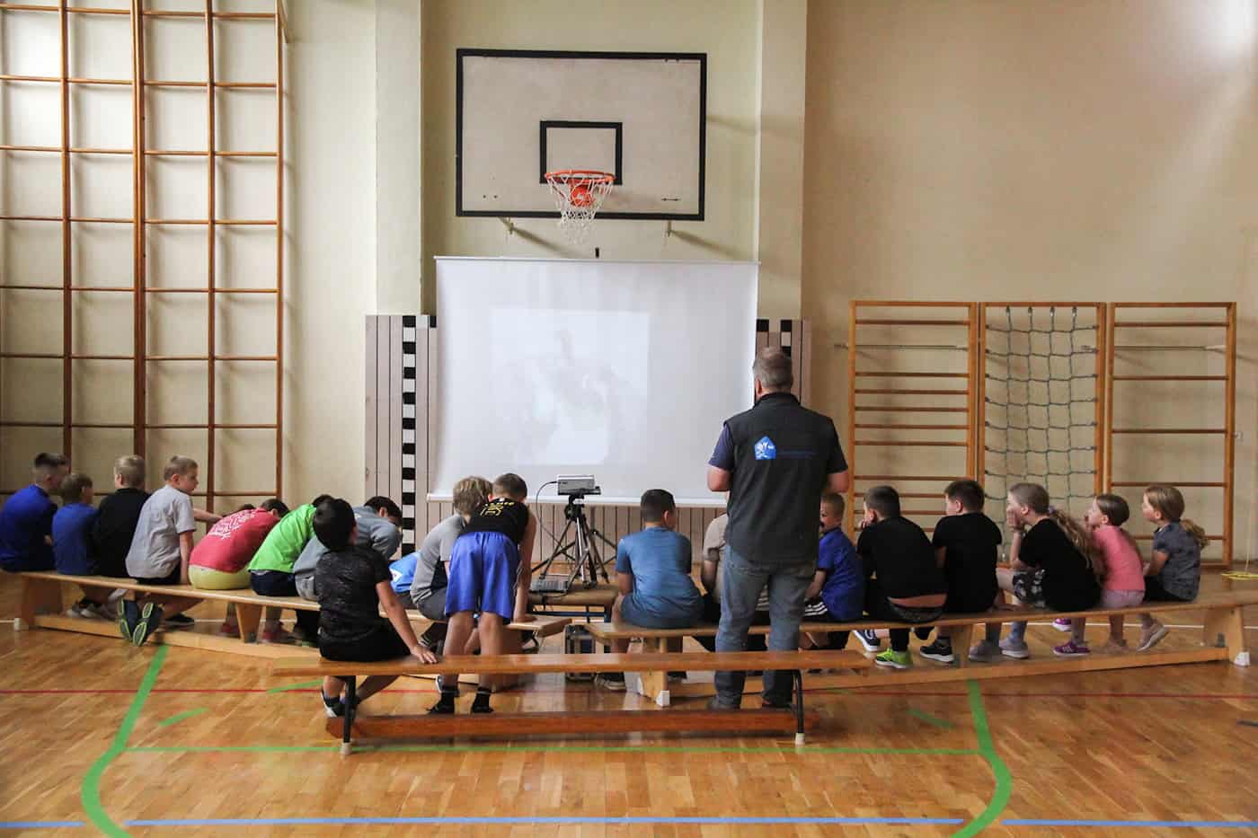 Andreas Färber ist mit den Kindern in der Sporthalle und schaut sich Fotos auf einer Leinwand an.