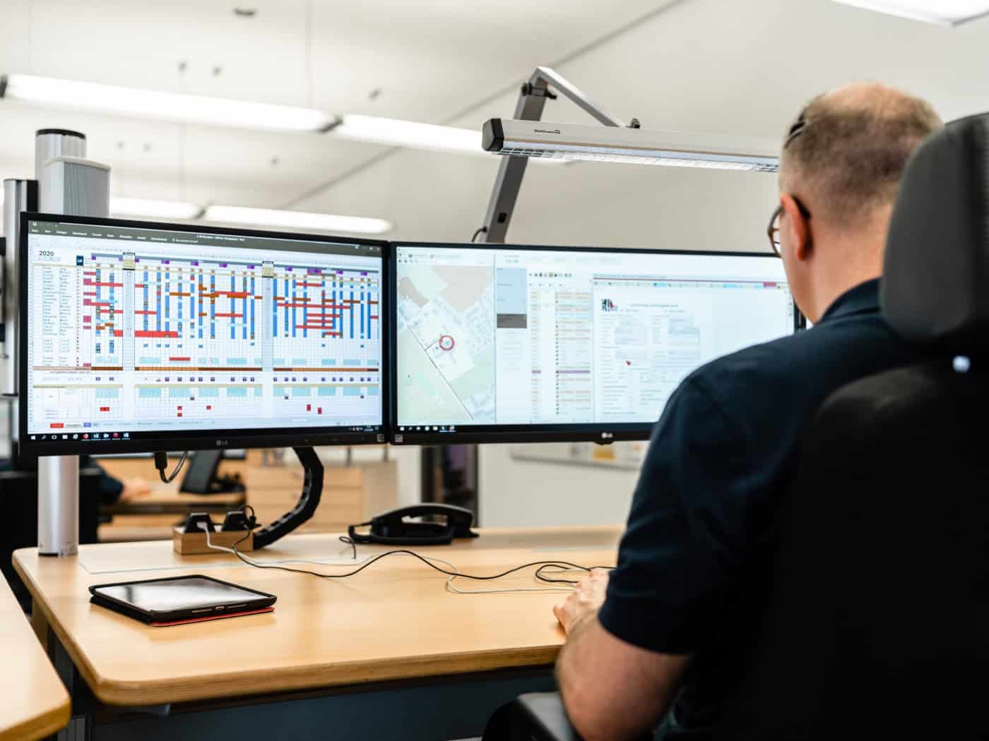 Ein Mitarbeiter der Dresdner Leitstelle sitzt vor mehreren Bildschirmen mit Einsatzplänen und digitalen Karten zur Koordination von Rettungseinsätzen.