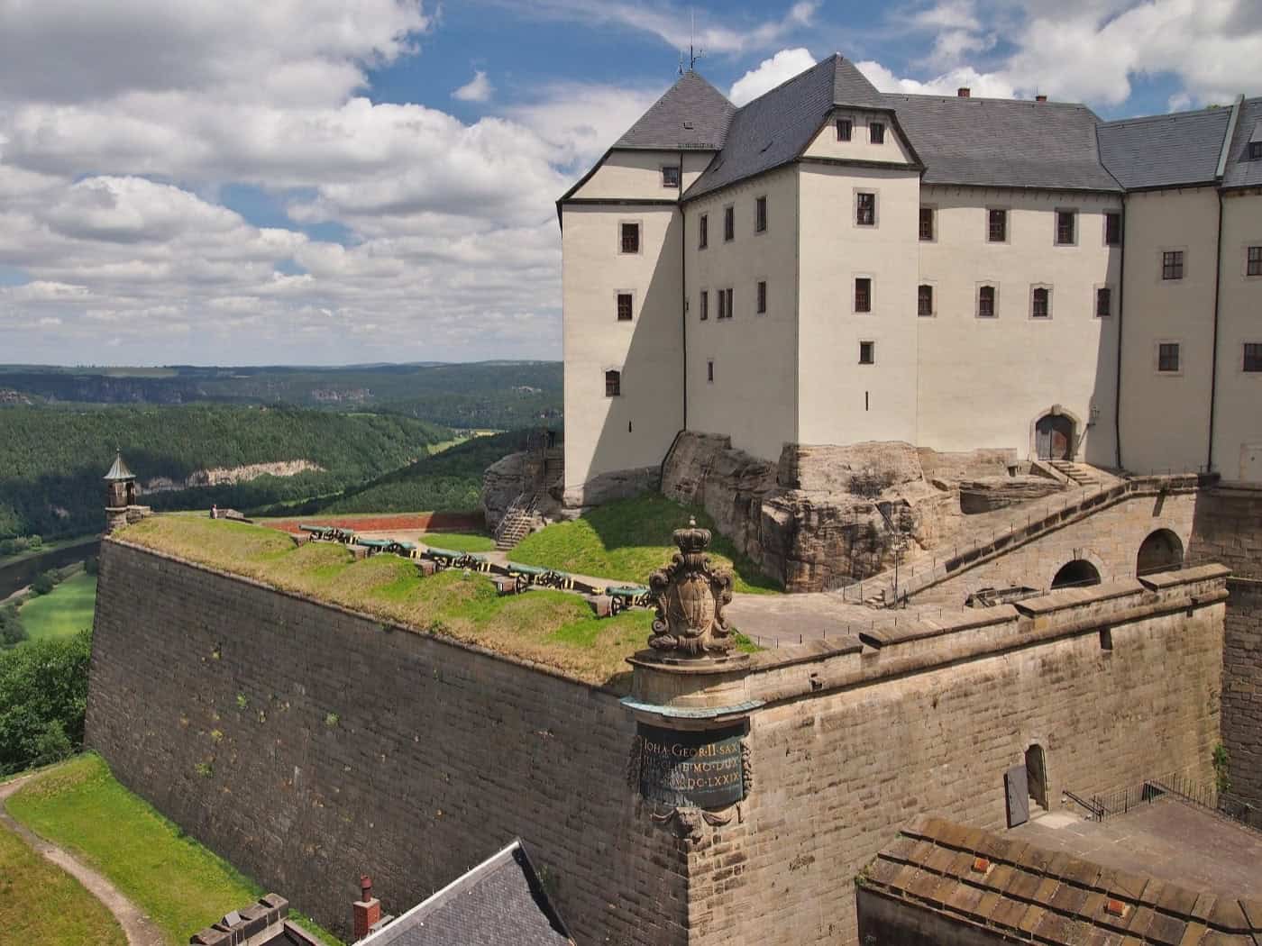 Blick auf die Festung Königstein mit historischen Mauern, Kanonen und einem weiten Panorama über die grüne Elblandschaft.