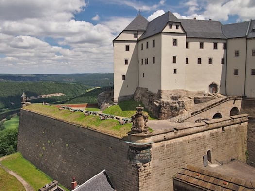 Blick auf die Festung Königstein mit historischen Mauern, Kanonen und einem weiten Panorama über die grüne Elblandschaft.