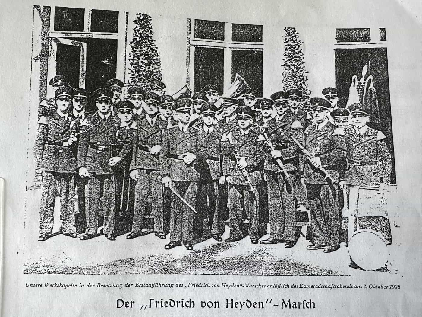 Kopie eines Zeitungsartikels von 1936 mit Titel "Der Friedrich von Heyden-Marsch" und einem abgedruckten Foto einer Musikkapelle mit zwei Dutzend uniformierten Musikern samt ihrer Blas- und Schlag-Instrumente
